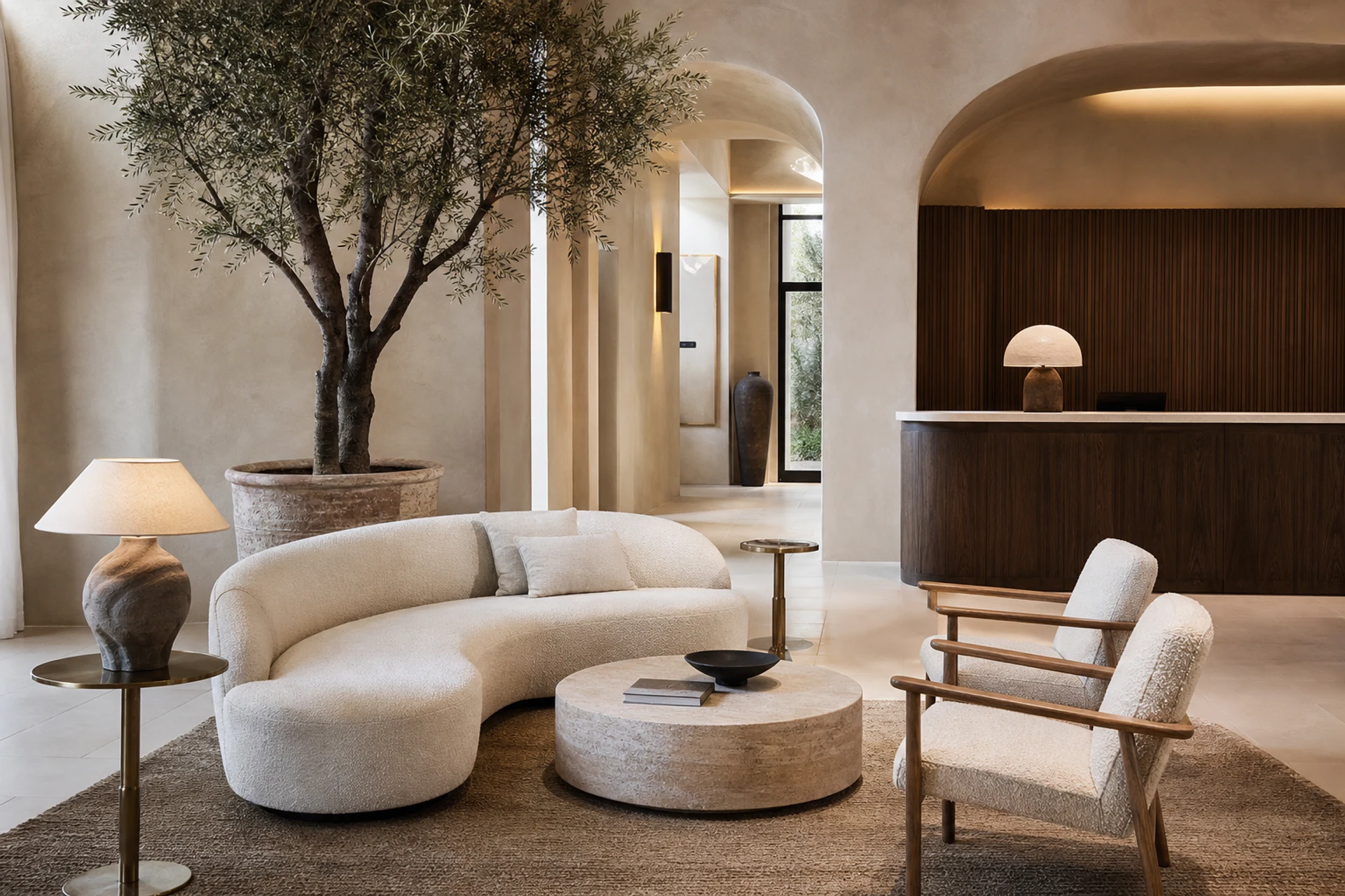 Contemporary Mediterranean hotel lobby with linen sofa, boucle lounge chairs, limestone coffee table, olive tree, and limewash walls