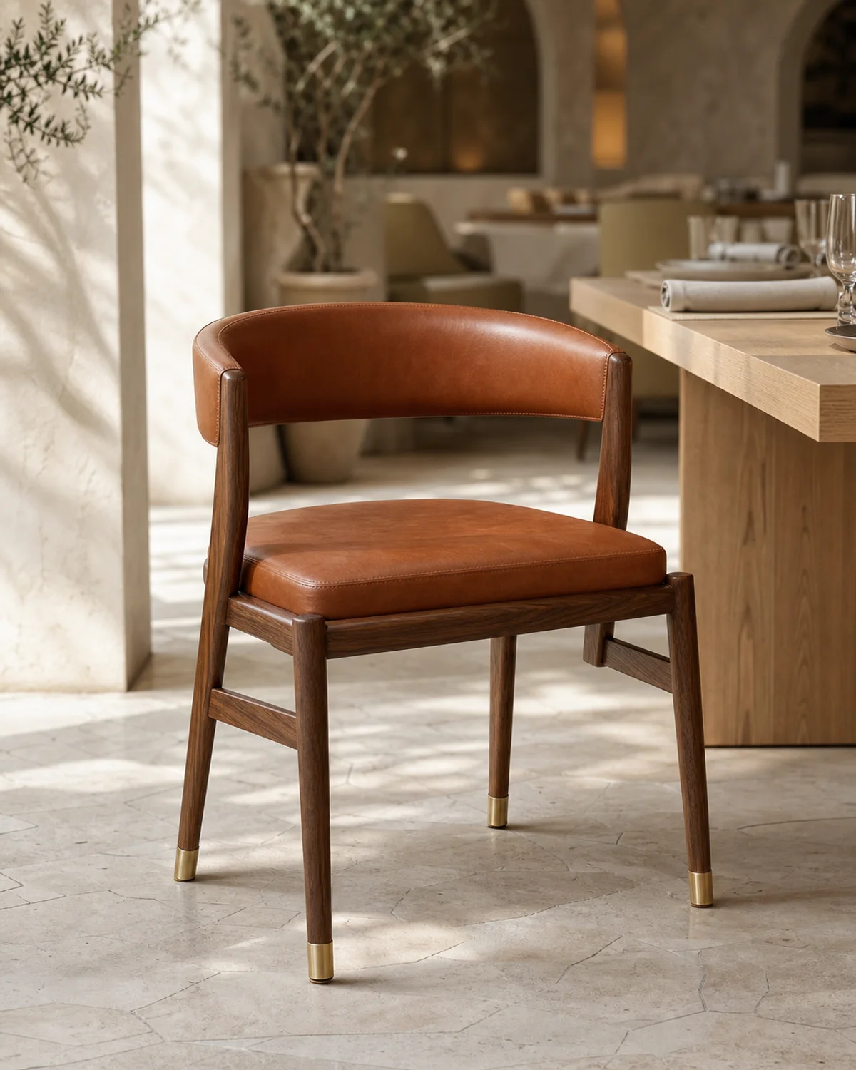 Cognac leather upholstered dining chair with walnut frame and brass ferrules — Mediterranean hotel lookbook